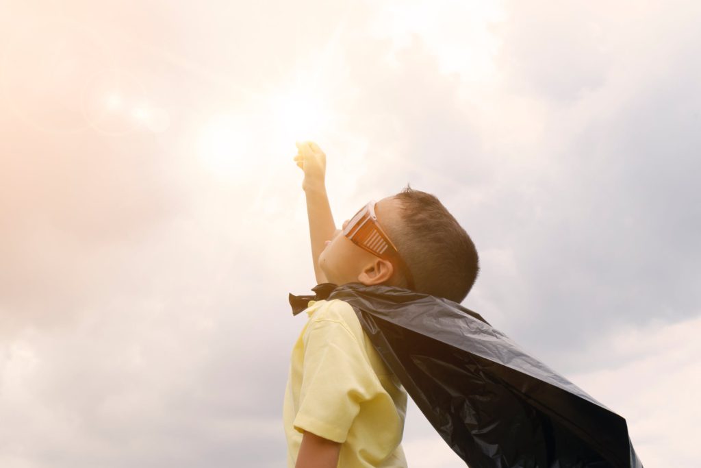 Kindje wijst met vuist naar de lucht zoals superman en kijkt naar de toekomst.